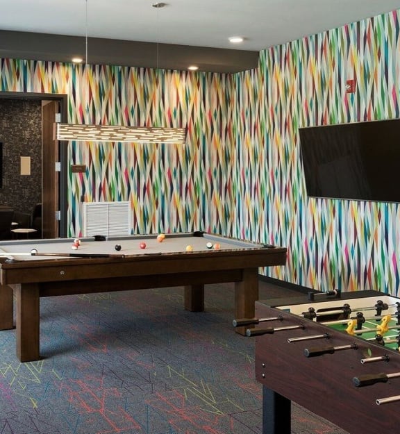 A pool table with a colorful striped wallpaper in the background at Era on Excelsior, St. Louis Park, Minnesota