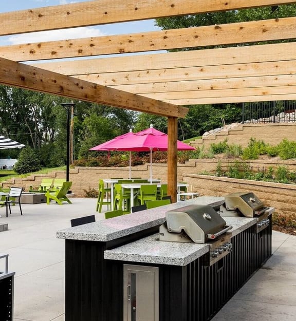A bar area with a pink umbrella and green chairs at Era on Excelsior, St. Louis Park, Minnesota