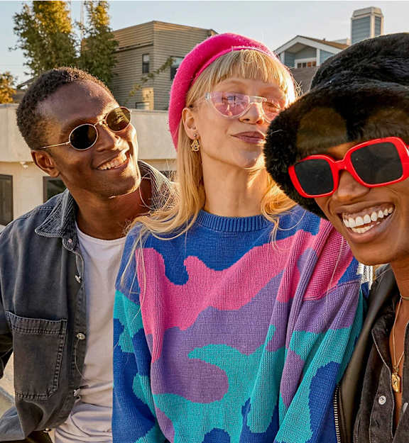 Three people wearing sunglasses and hats are standing together.