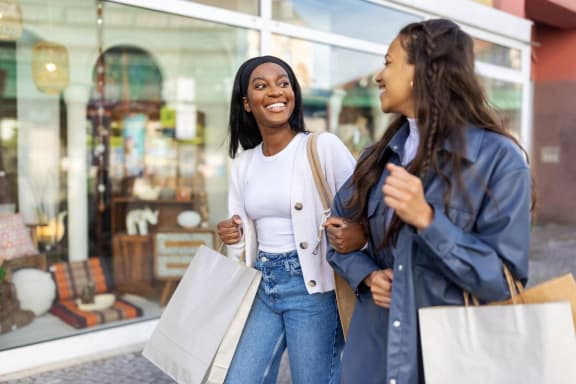 two women walking down the street with shopping bags