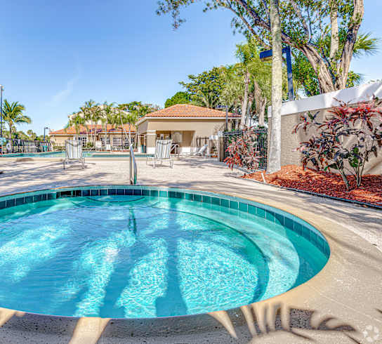 a round swimming pool with palm trees and a building in the background