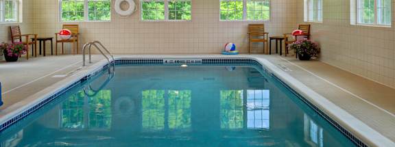 A large indoor swimming pool with a sunny day outside.