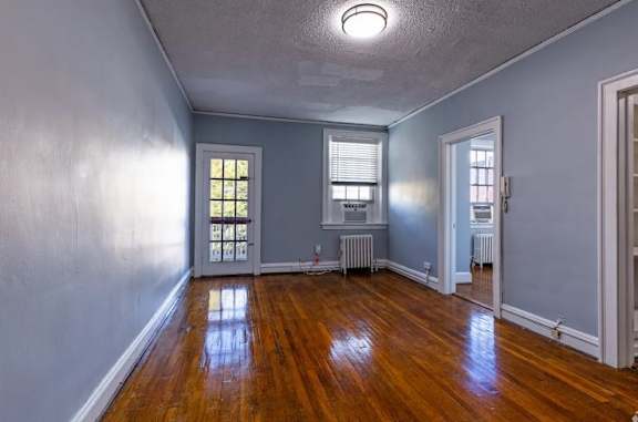 A room with wooden floors and a window with blinds.