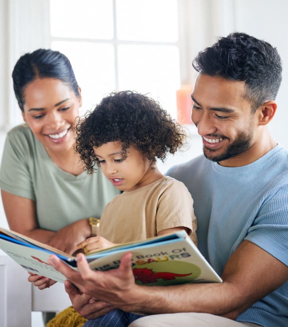a young boy reading a book with his parents