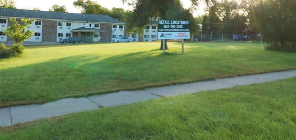 a sign in the grass in front of an apartment building