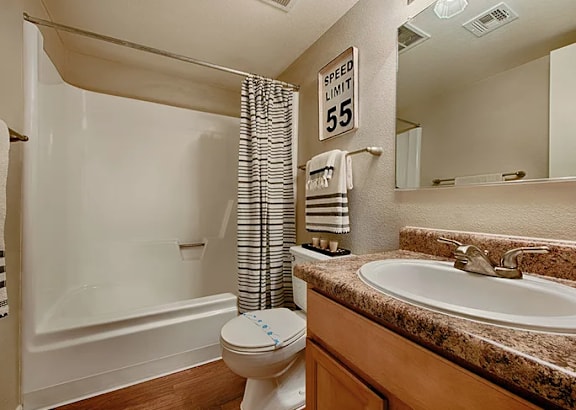 A bathroom with a toilet, sink, and a speed limit sign. at Sycamore Square  Apartments, Arizona, 85202