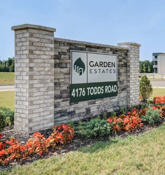 A sign for Garden Estates at 4176 Todds Road stands in front of a building.