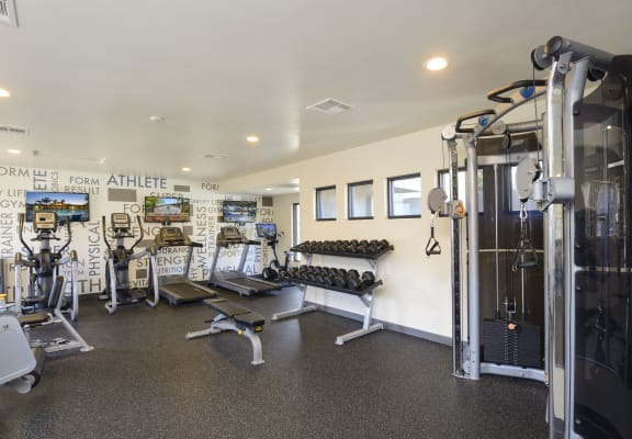 a gym with weights and cardio equipment and a wall of graffiti