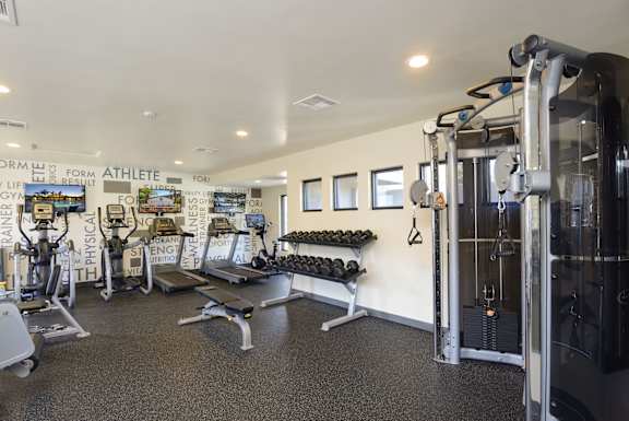 a gym with weights and cardio equipment and a wall of graffiti