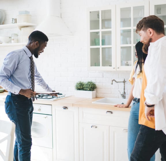 two men and a woman standing in a kitchen preparing food