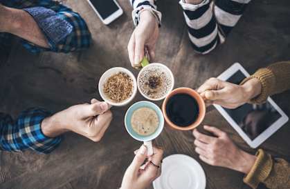 A group of people are gathered around a table, each holding a cup of coffee.