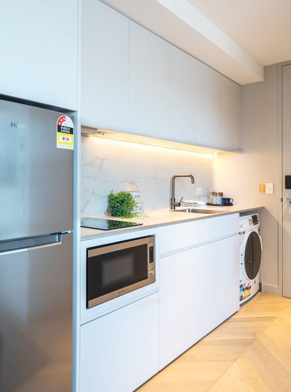 a white kitchen with a microwave and a refrigerator