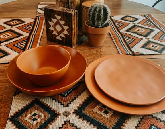 a wooden table topped with orange plates and a cactus