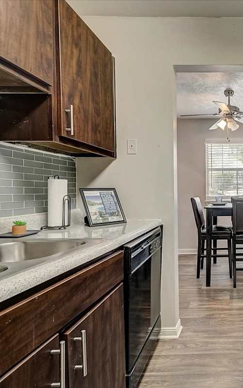 A kitchen with dark wood cabinets and a black refrigerator.