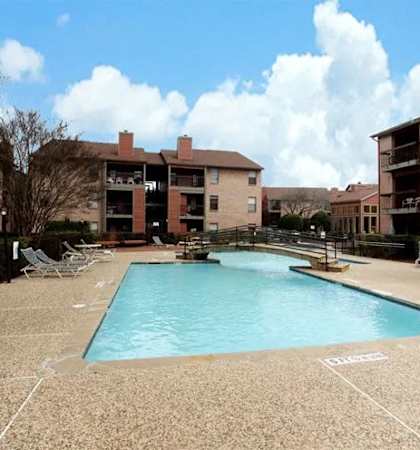 A pool surrounded by apartment buildings and picnic tables. at Brook Meadow Village Apartments , Austin, 78758