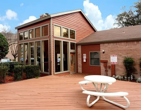 A red building with a white picnic table in front at Brook Meadow Village Apartments , Austin