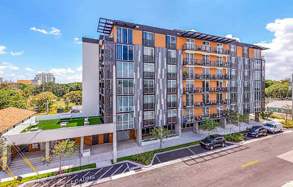 A modern multi-story building with orange and grey balconies.