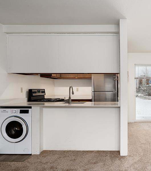 A kitchen with a washing machine in the corner.