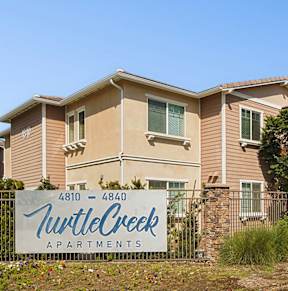 A sign for Turtle Creek Apartments is in front of a building.