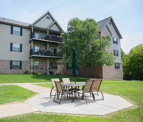 A patio table with chairs and an umbrella is in front of a building.