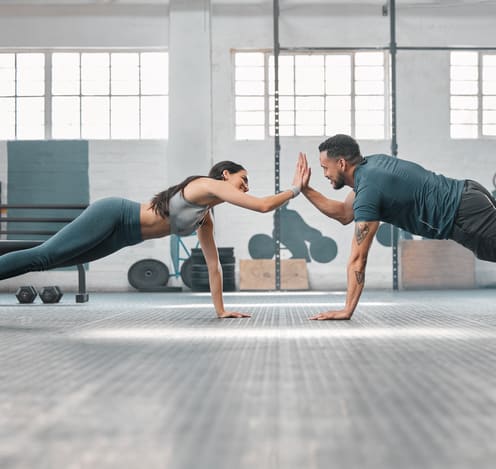 a man and a woman doing pushups in a gym