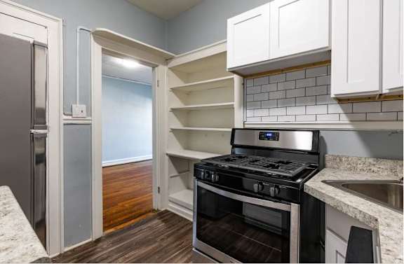 A kitchen with a stove, oven, and cabinets.