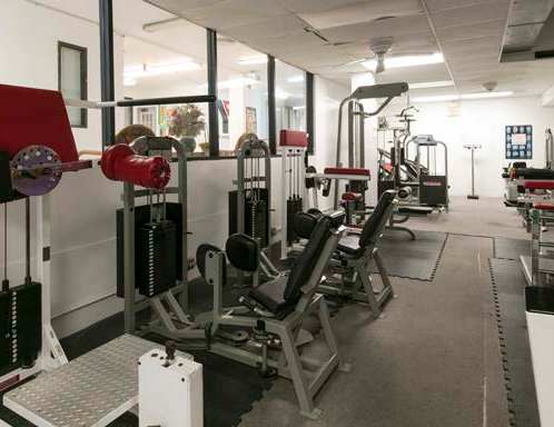 A gym with a variety of equipment including weight machines and free weights.