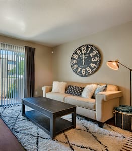 A living room with a couch, coffee table, and a clock on the wall. at Sycamore Square  Apartments, Arizona, 85202