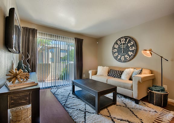 A living room with a couch, coffee table, and a clock on the wall. at Sycamore Square  Apartments, Arizona, 85202