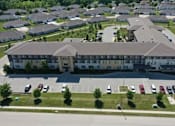 Thumbnail 2 of 12 - A large building with a parking lot in front of it.