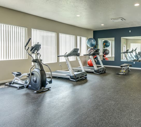a gym with exercise equipment on the floor and windows