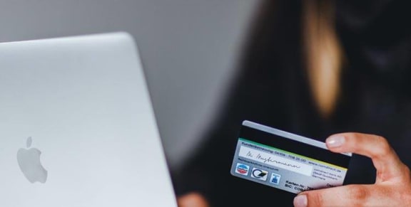 Person holding a credit card next to a laptop at Avilla Grand in El Mirage, AZ.