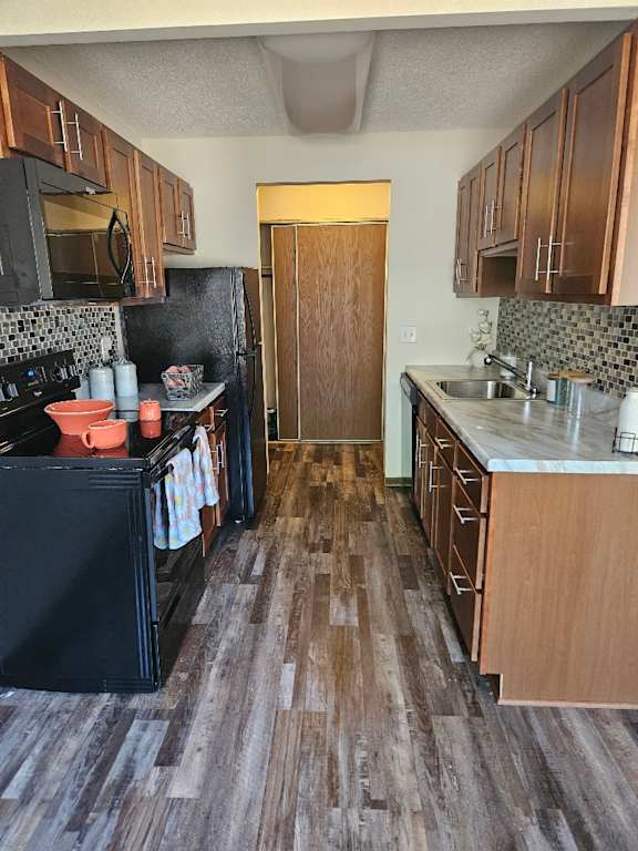 A kitchen with a black fridge, microwave, and oven.