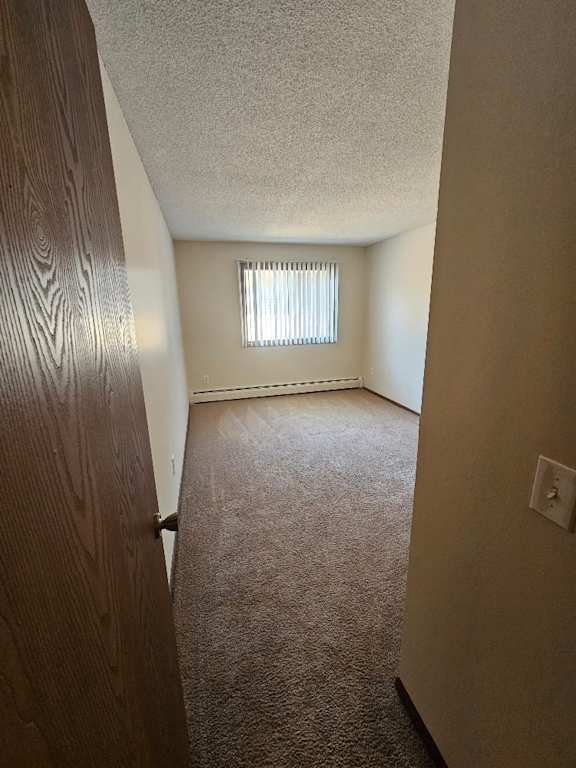 A room with a carpeted floor and a window with blinds.