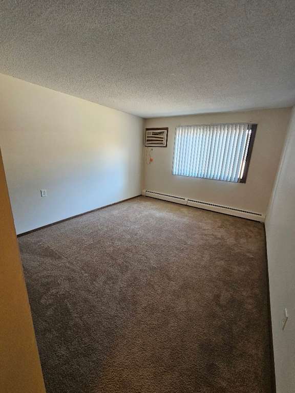 A room with a carpeted floor and a window with blinds.