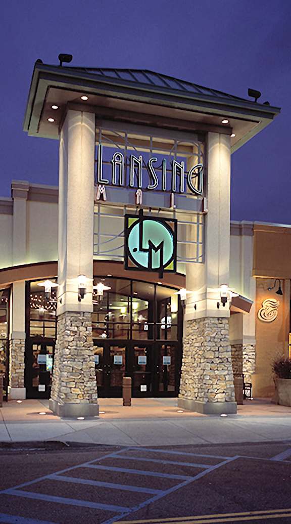 The entrance to a business with a stone pillar and a lit up sign.