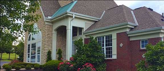 A house with a red brick exterior and a green roof.