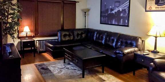 A black leather couch sits in a living room with a coffee table in front of it.