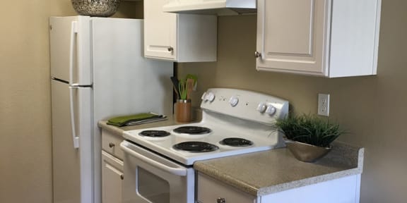 a small kitchen with a stove and a refrigerator at Seabreeze Apartment Homes, Vallejo, CA