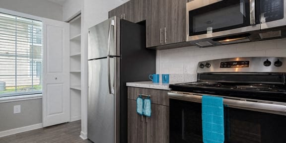 a kitchen with a stove refrigerator and microwave and a window