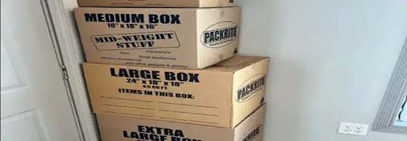 A stack of three boxes labeled "Smart Box," "Medium Box," and "Large Box" are stacked on top of each other in a room with a white door and tiled floor.