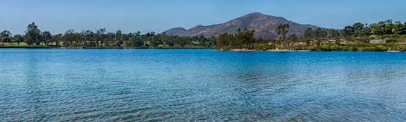 A serene lake with a mountain in the distance under a clear blue sky.