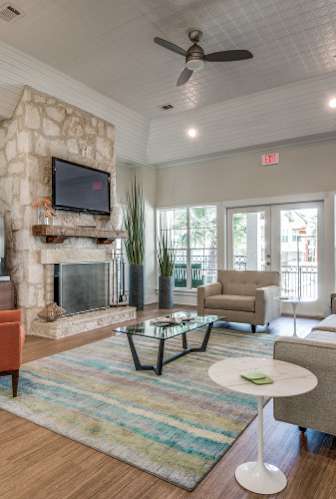 A living room with a stone fireplace and a flat screen TV mounted above it.