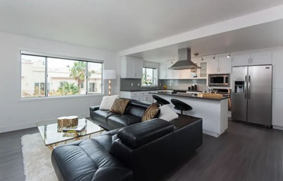 A modern kitchen with a black leather couch and a coffee table.