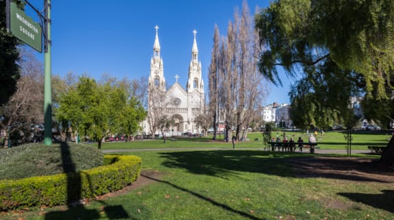 a park with trees and grass in front of a cathedral