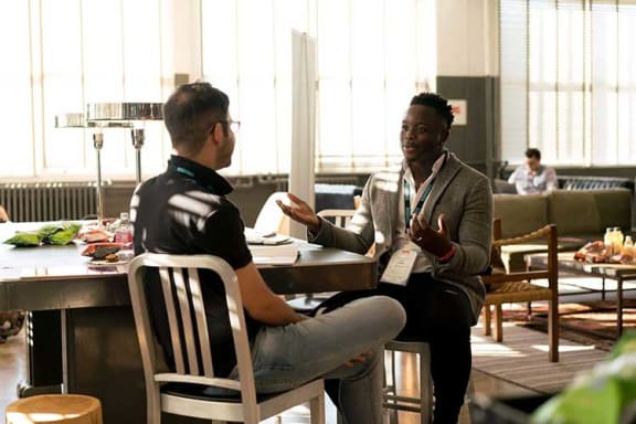 two men sitting at a table talking to each other