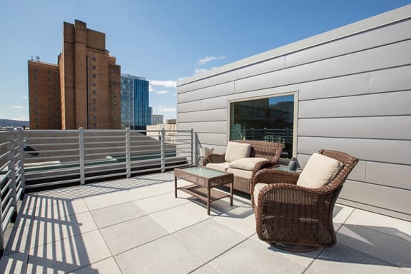 a roof deck with chairs and a view of the city