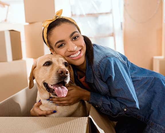 a woman with a yellow dog in a cardboard box