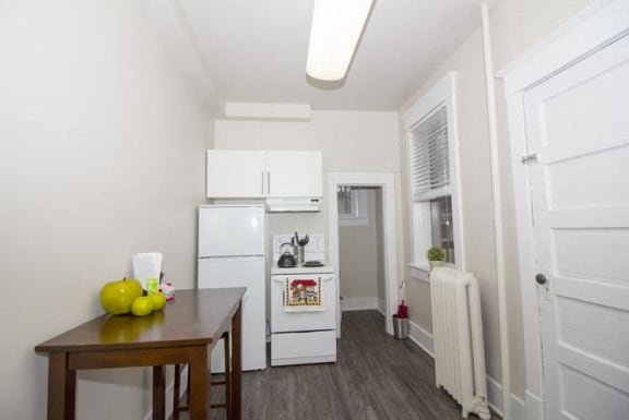 a small kitchen with white appliances and a wooden table
