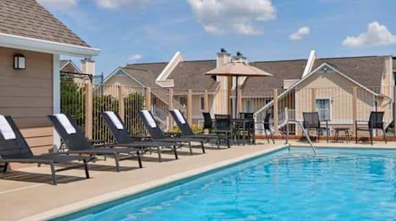 a swimming pool with lounge chairs next to a building